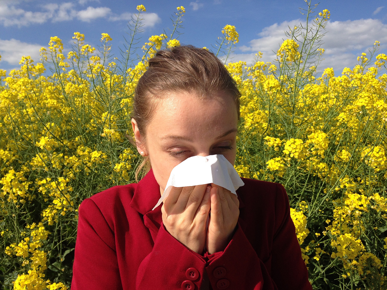 a woman in a field of flowers blowing her nose into a tissue