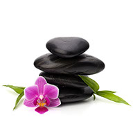 3 smooth black stones stacked and 1 pink flower